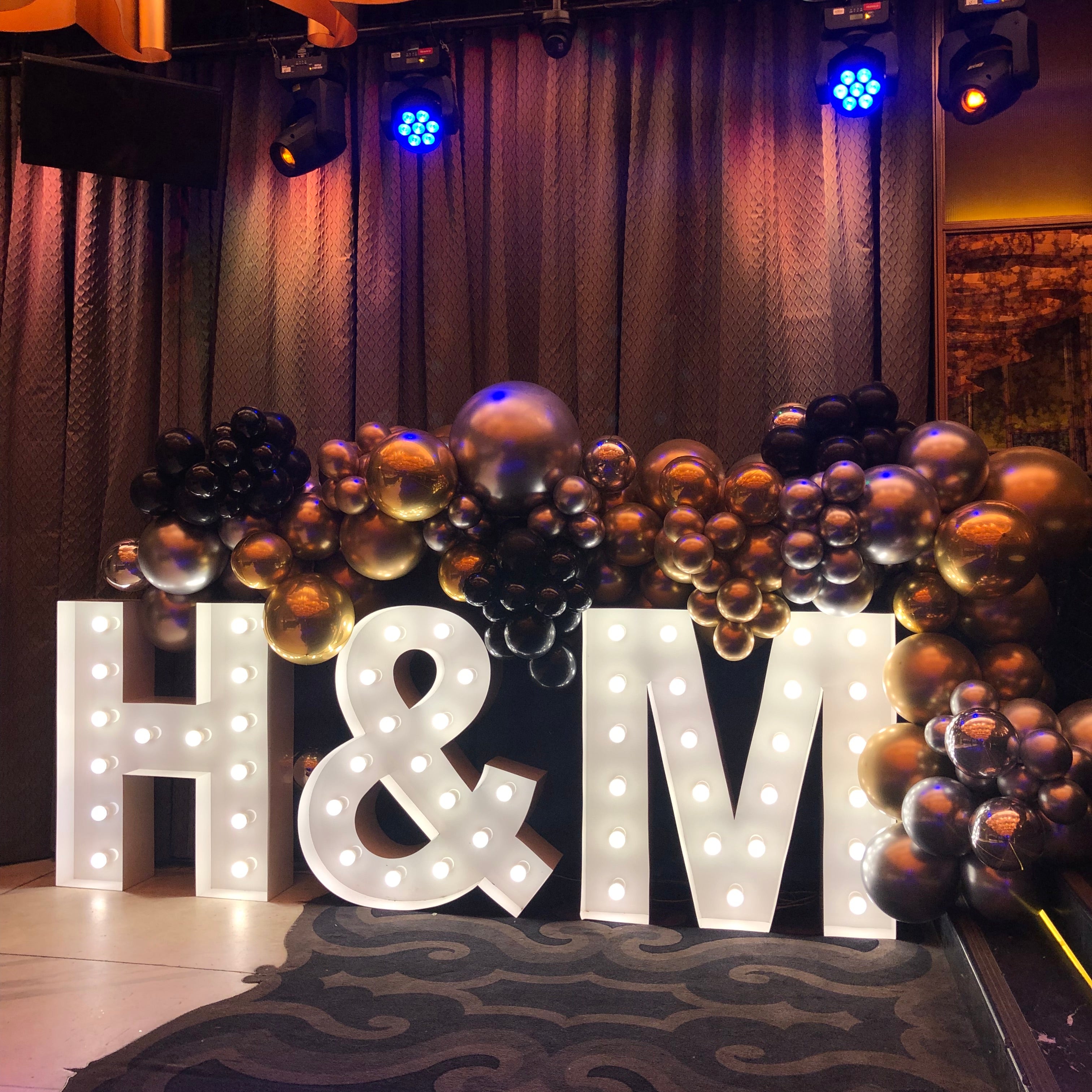 Decorative setup with balloons and 1m illuminated letters spelling 'H&M'