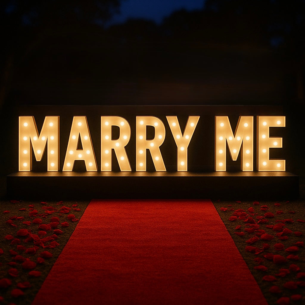 Proposal package with large illuminated letters spelling 'MARRY ME' on a red carpet.