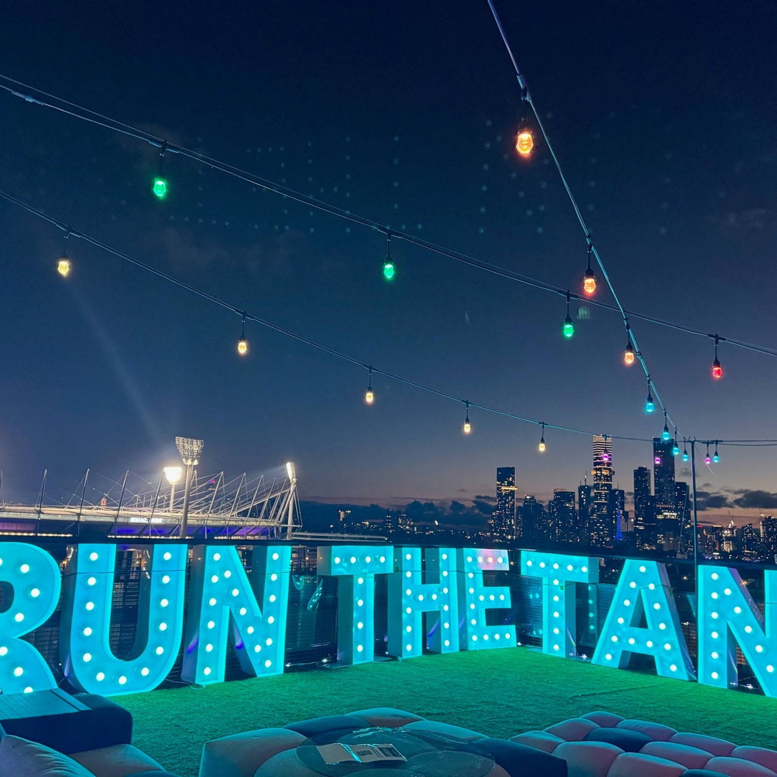aqua blue globe light up letters RUN THE TAN in front of MCG