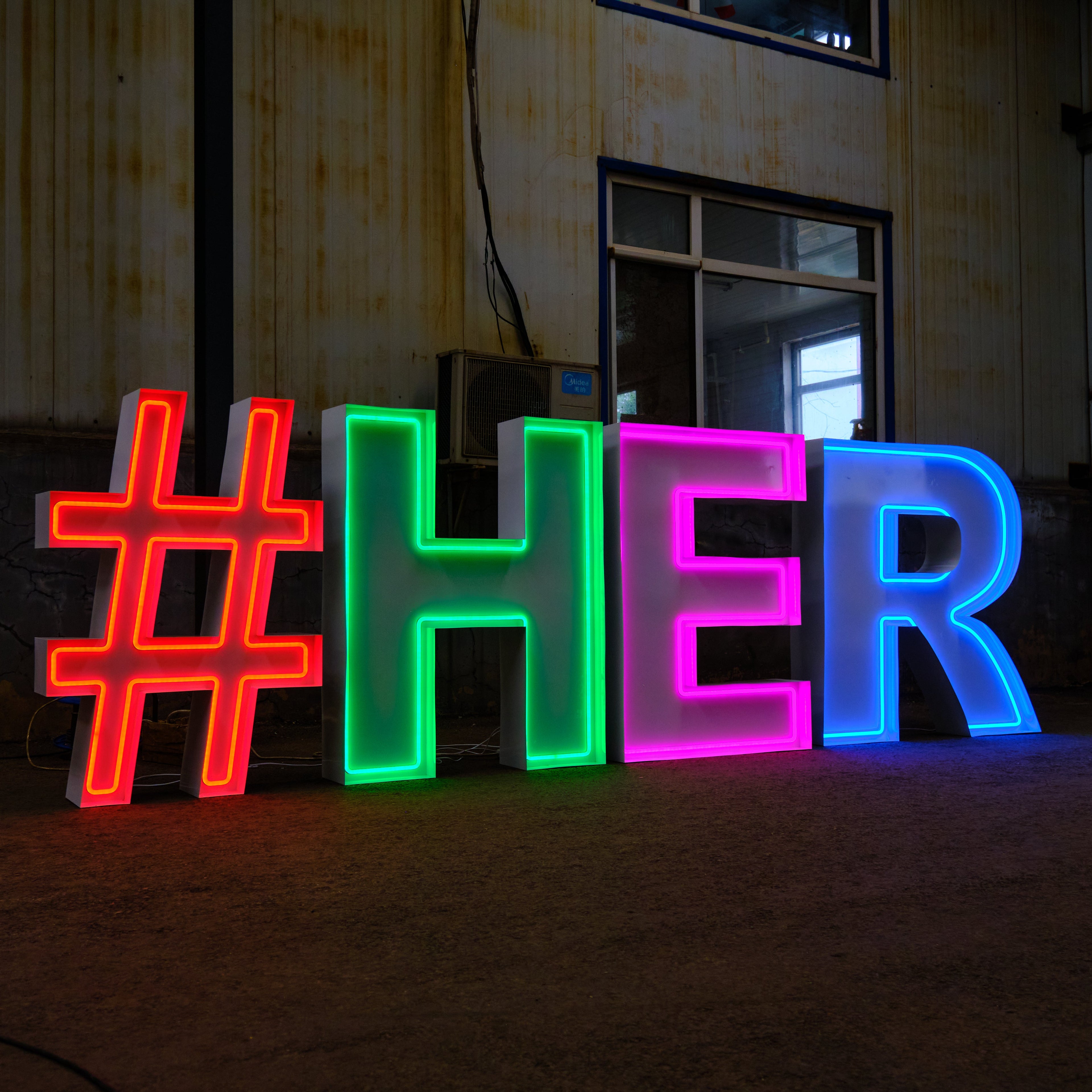 Neon letters with '#HER' in a dark indoor setting