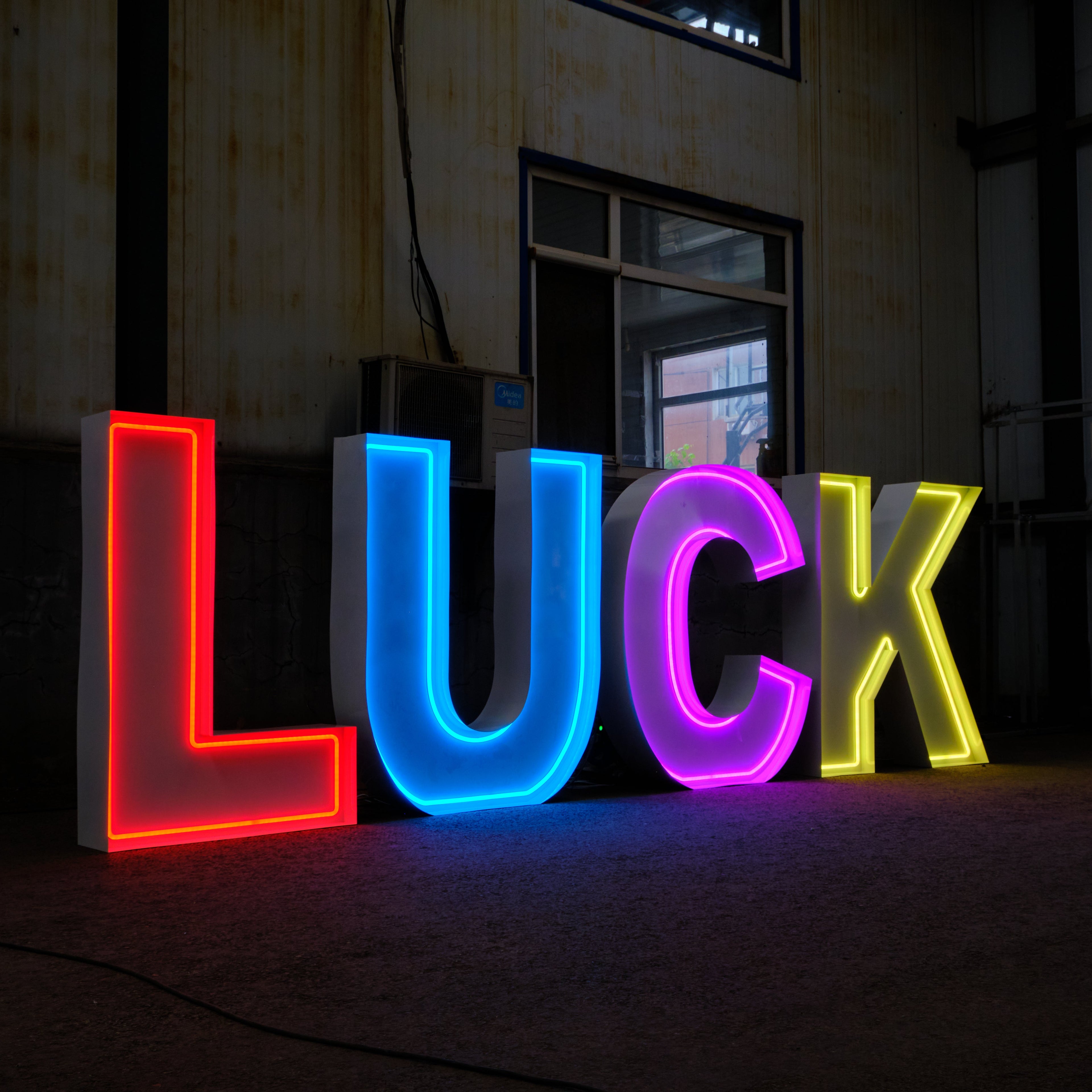 Neon sign spelling 'LUCK' in red, blue, pink, and yellow on a dark background.