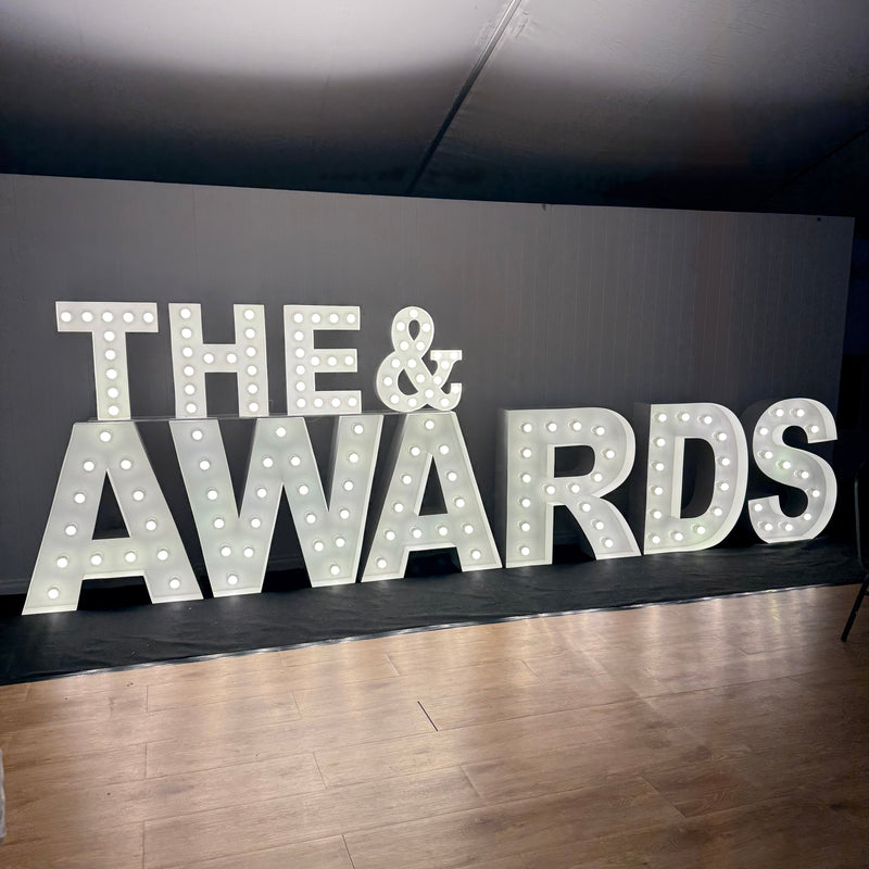 60cm 'The &' elevated and stacked on 1m 'AWARDS'. Illuminated letters set along a black carpet runner. The letters light up the marquee floor drawing a focal photo opportunity. 