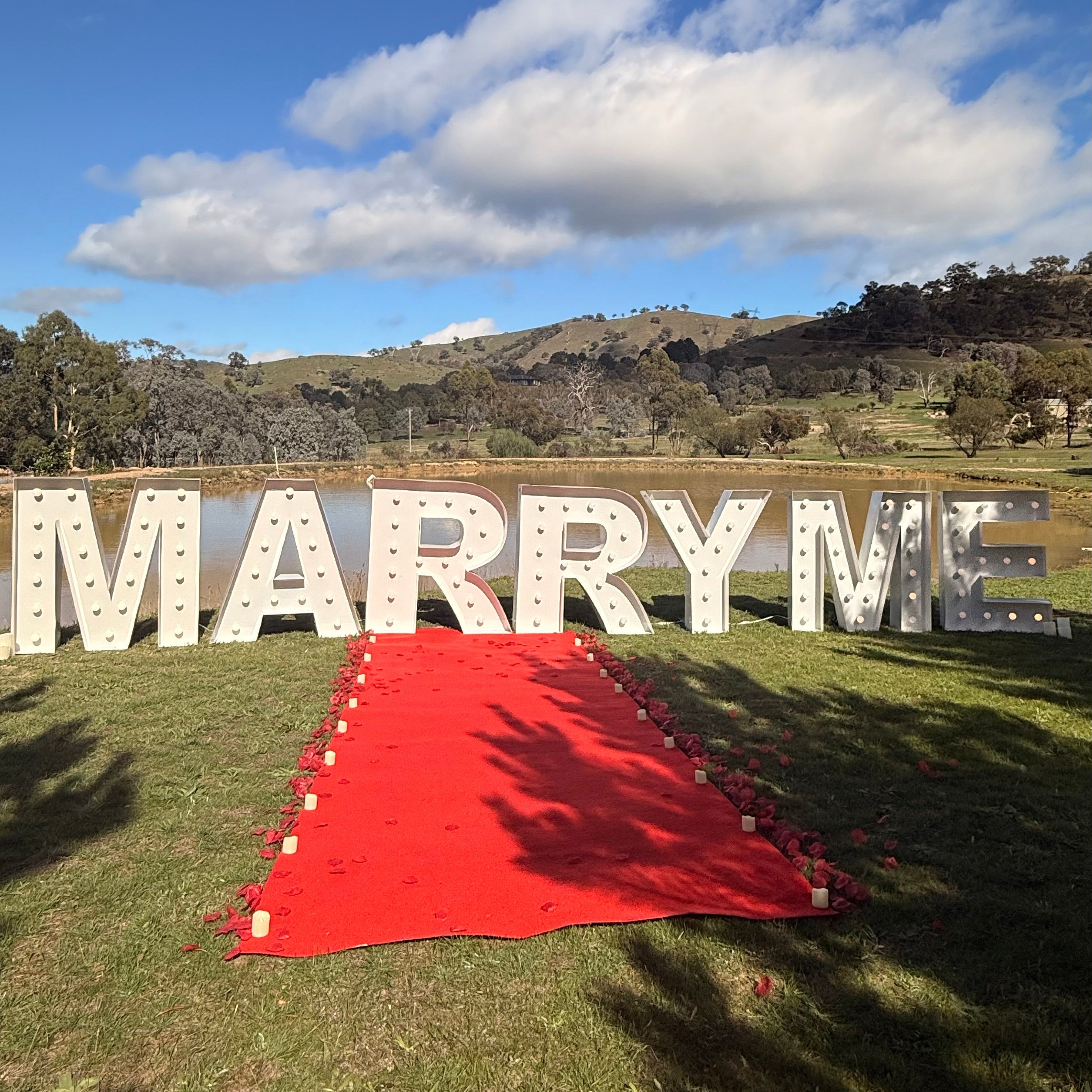 Marry_Me_Proposal_Package Proposal Letters with Red Carpet, Candles and Rose Petals with a view of the mountains behind it. 